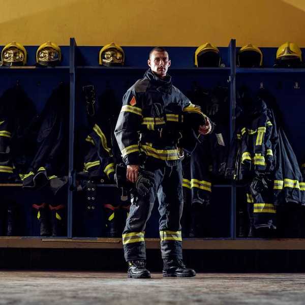 Firefighter clad in turnout gear standing in front of gear cubbies