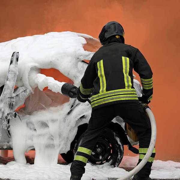 Firefighter demonstrating extinguishing a car fire with aqueous firefighting foam.