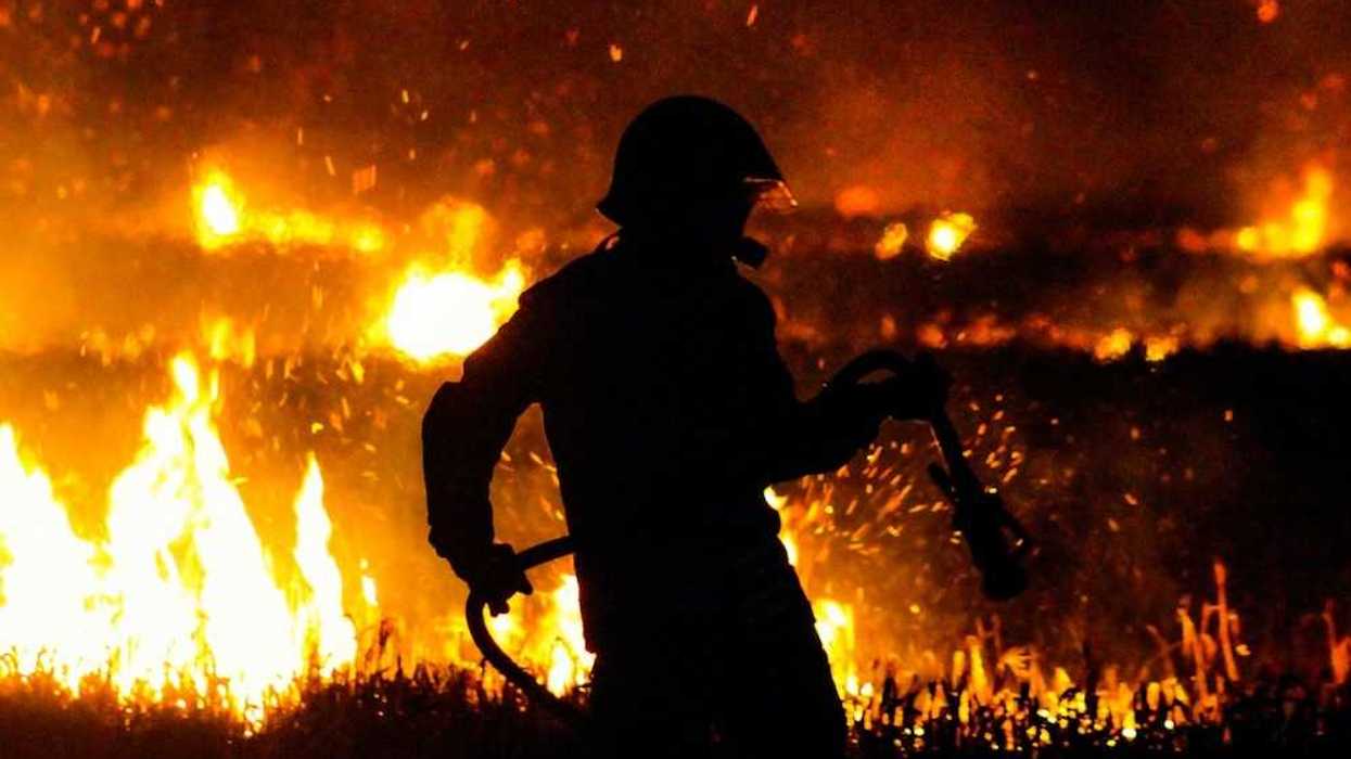 Firefighter silhouetted against flames at night