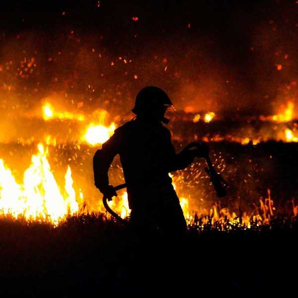 Firefighter silhouetted against flames at night