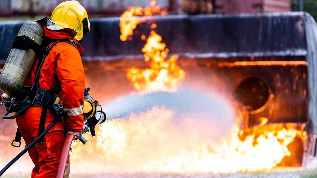 Firefighter using Chemical foam fire extinguisher to fighting with the fire flame from oil tanker truck accident.