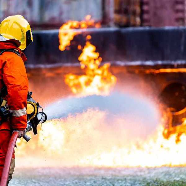 Firefighter using Chemical foam fire extinguisher to fighting with the fire flame from oil tanker truck accident.