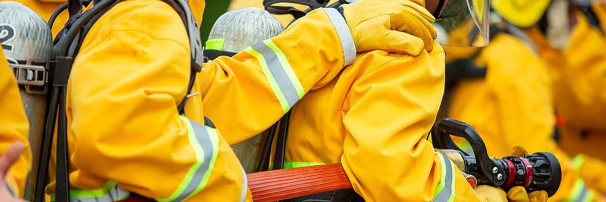 Firefighters holding red fire hose
