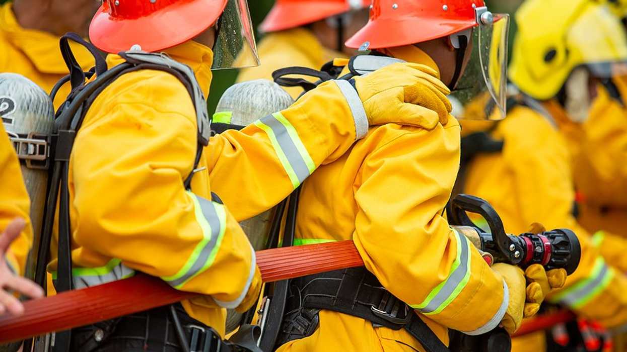 Firefighters holding red fire hose