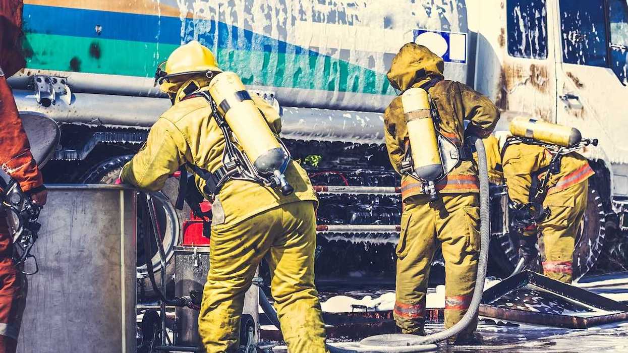 Firemen in firefighter uniforms during fire drill and training for safety with foam and chemical fire suppression systems.