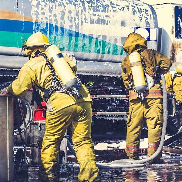 Firemen in firefighter uniforms during fire drill and training for safety with foam and chemical fire suppression systems.
