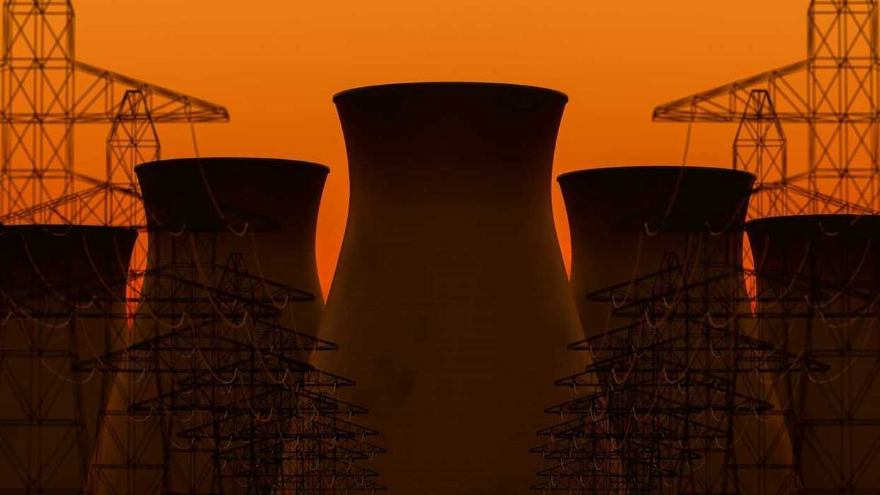 Five nuclear power plant cooling towers sillhouetted against transmission lines and orange sky
