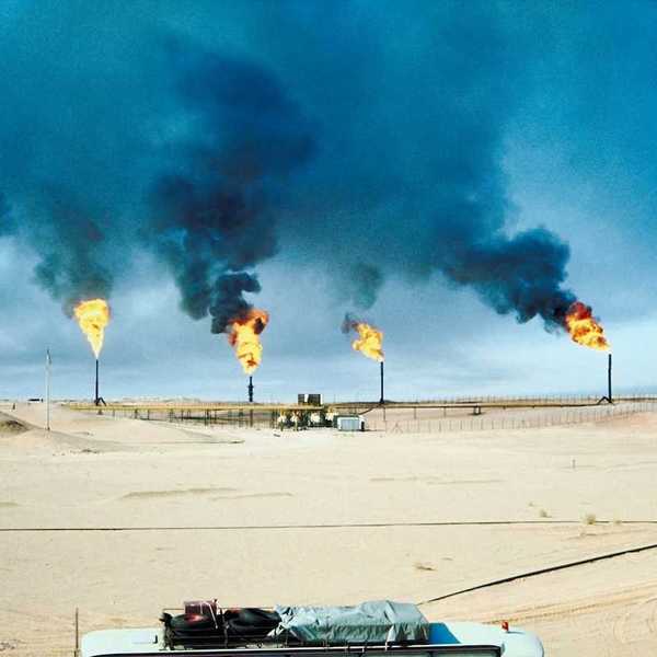 Five oil and gas wells burning off methane in a desert (Middle East?) environment.