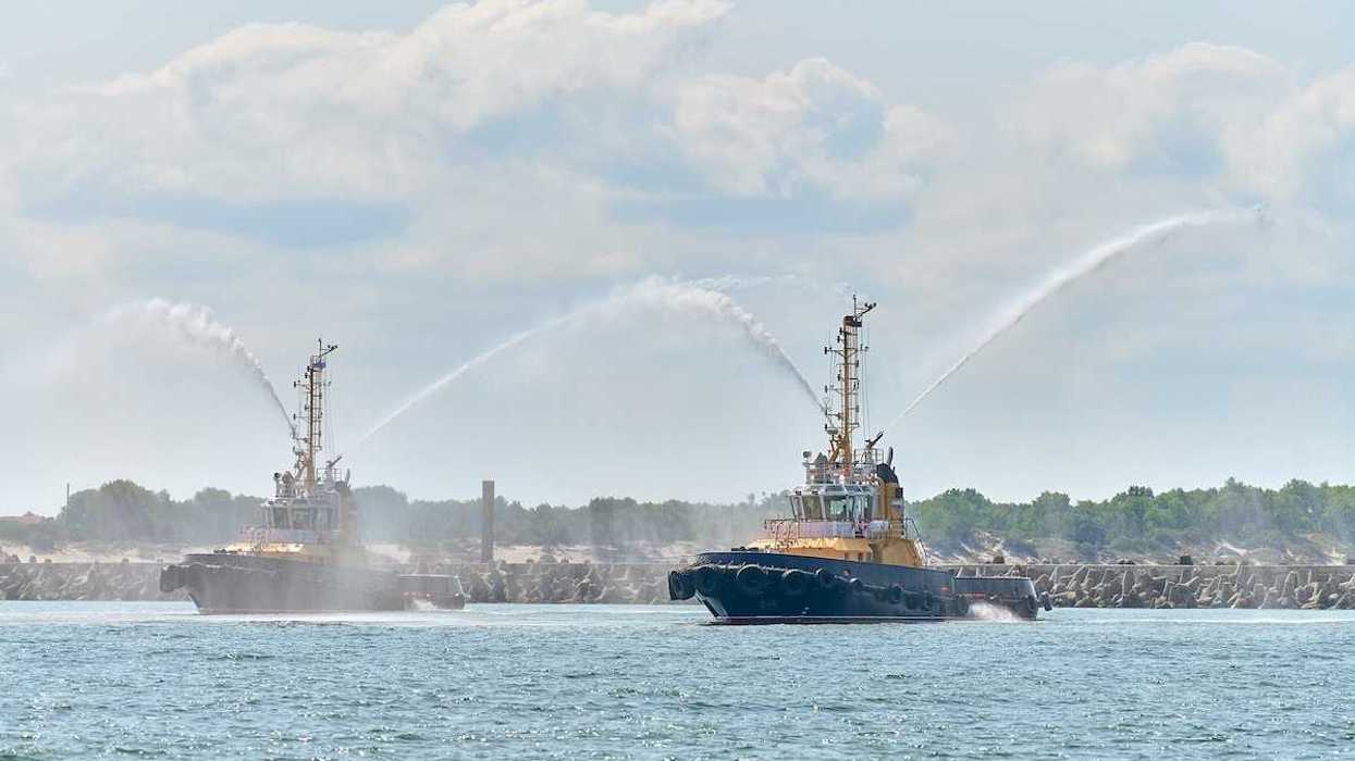 Floating tug boats spraying jets of water or firefighting foam, demonstrating firefighting water cannons.
