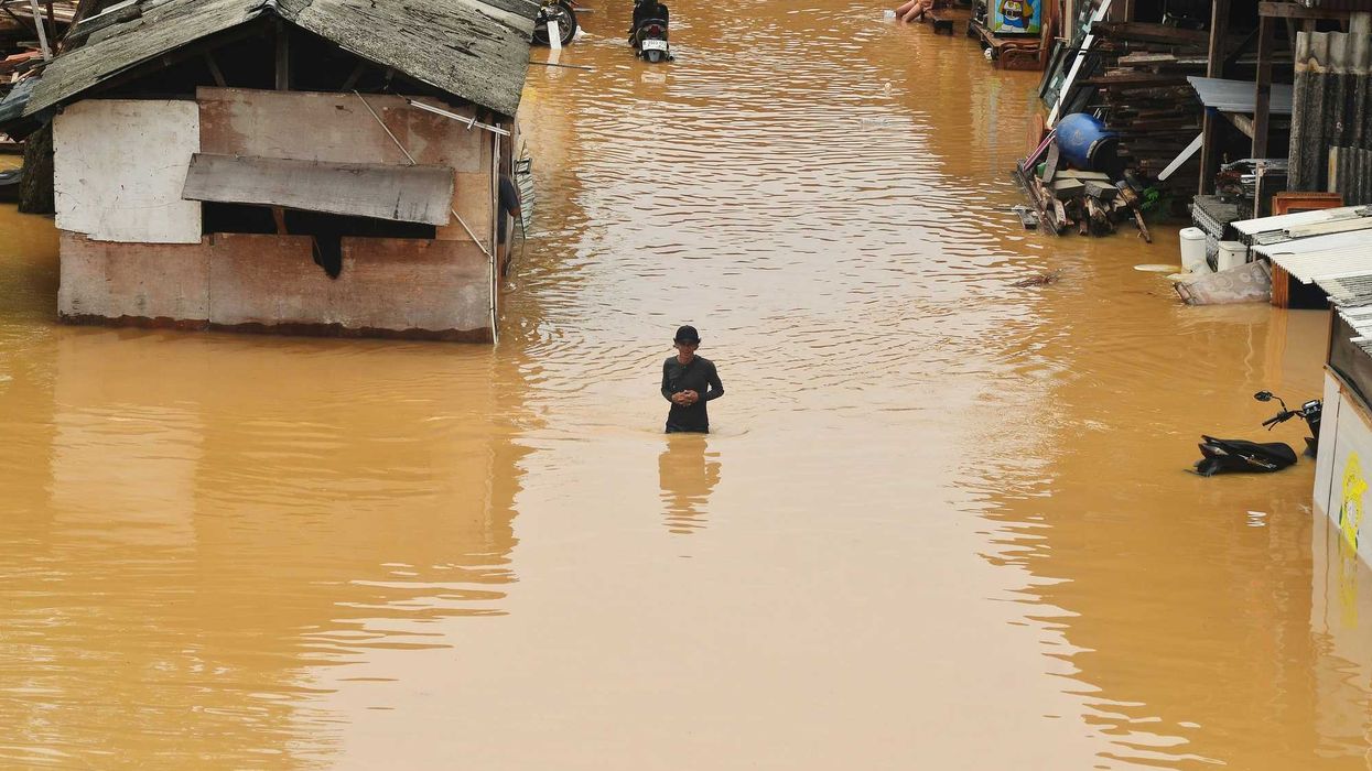 Flooding engulfs homes and a person stands in the water.