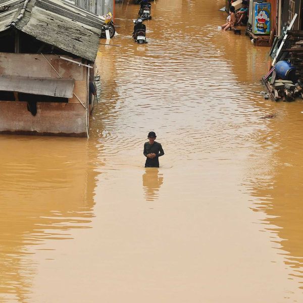 Flooding engulfs homes and a person stands in the water.
