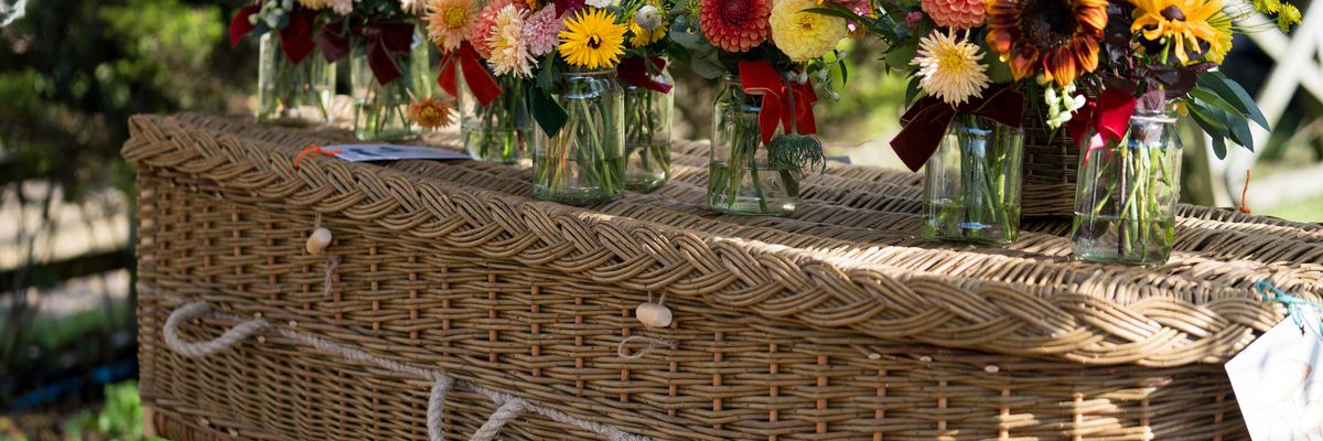 Flowers adorn a wicker coffin at a celebration.