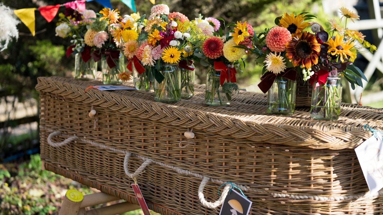 Flowers adorn a wicker coffin at a celebration.