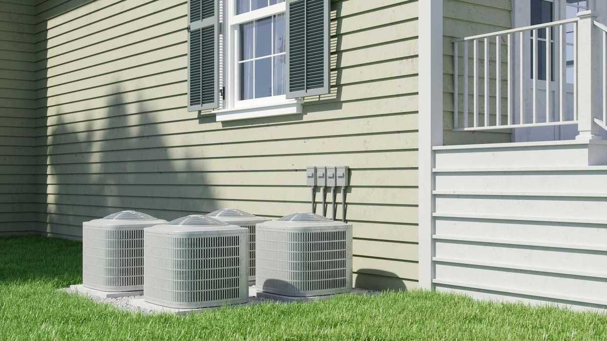 Four air conditioning units positioned next to a residential structure