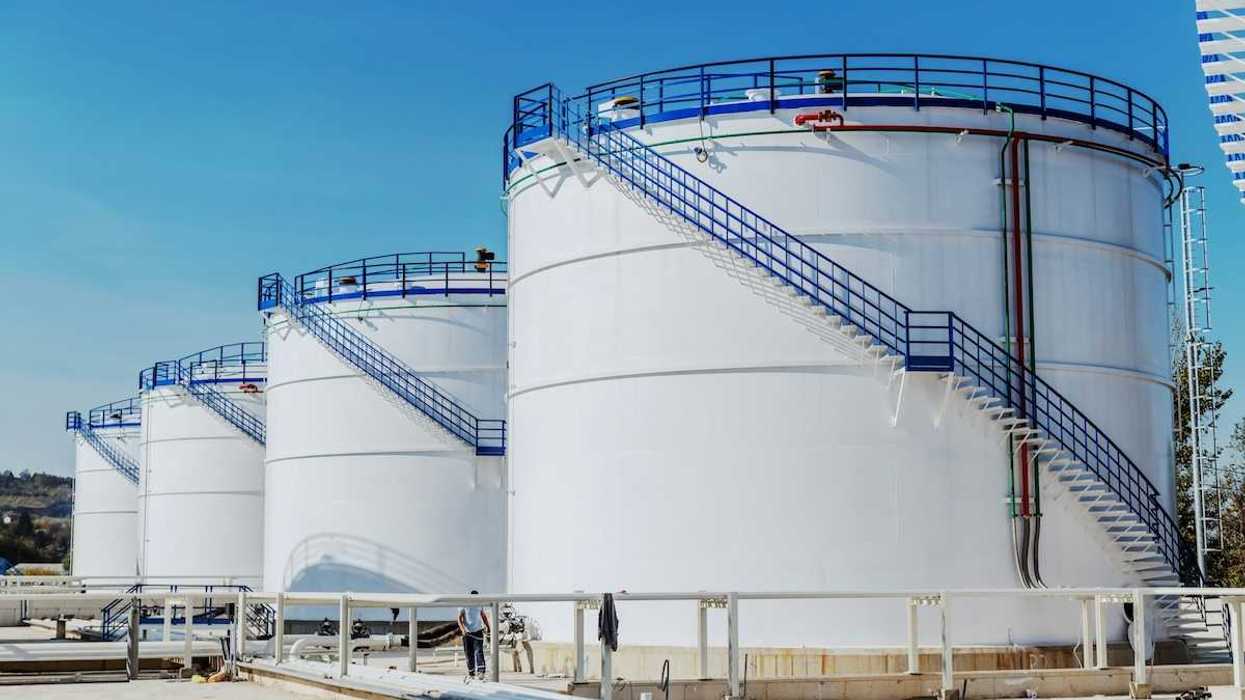 Four large white chemical storage tanks