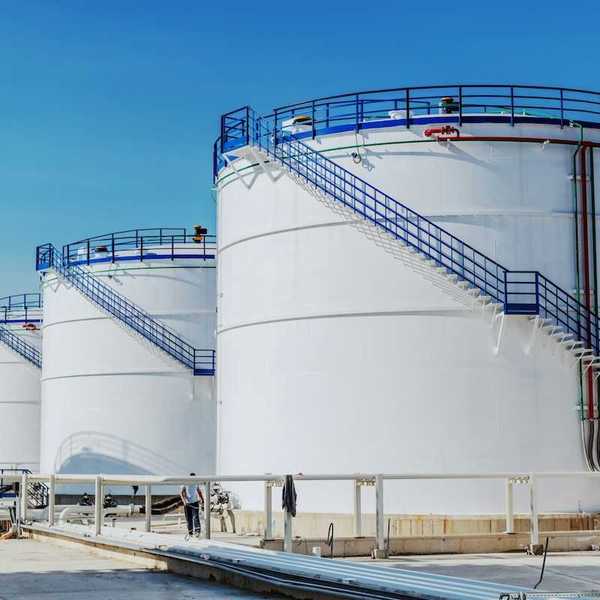 Four large white chemical storage tanks