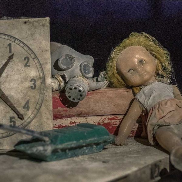 gas mask, doll, toy tank, and clock reading 1:23 symbola of Chernobyl and children