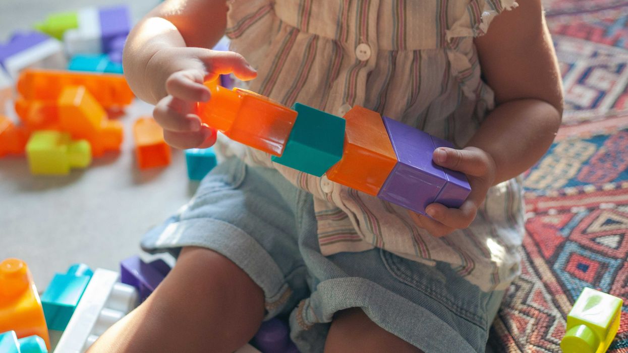 girl in brown button up shirt holding blue and orange plastic toy