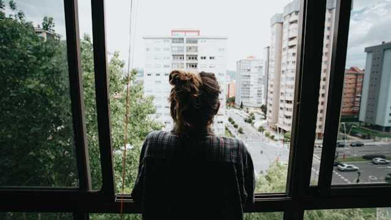 Girl looking out of her window in the city