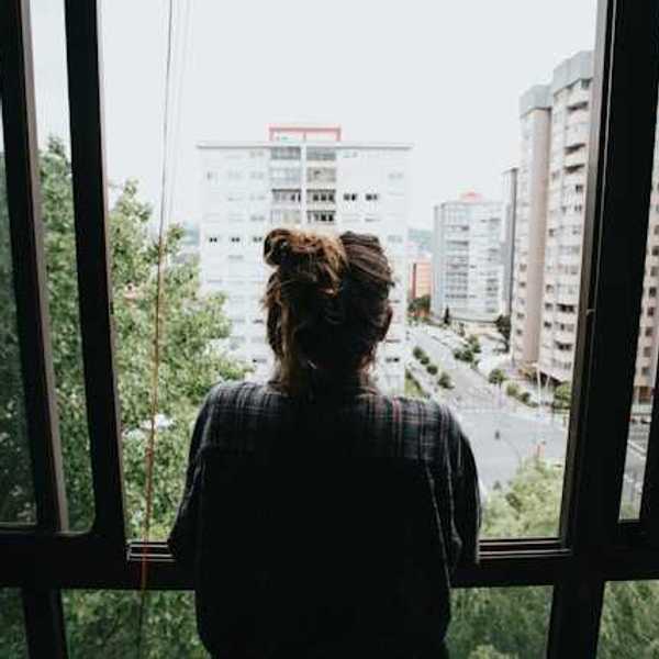 Girl looking out of her window in the city