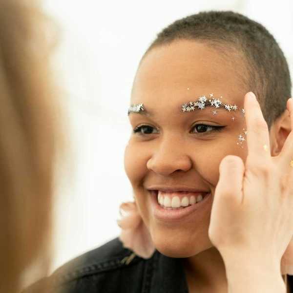 Glitter being applied to person's eyebrows and face