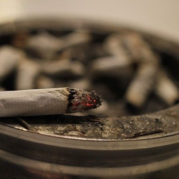 Glowing cigarette on an ashtray.