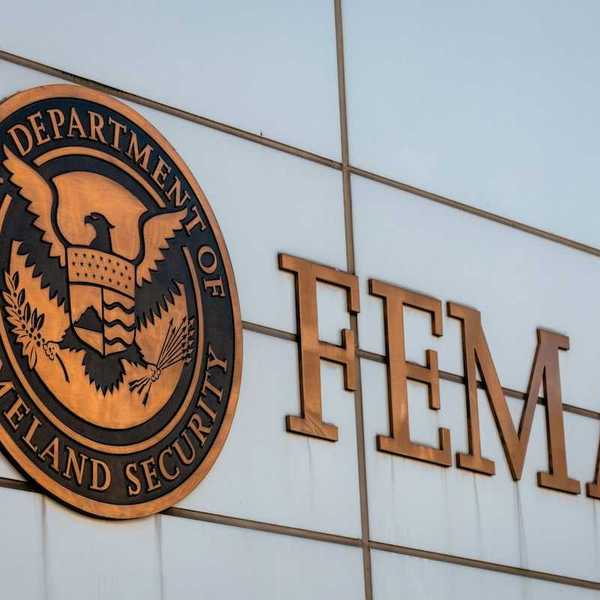 Gold-colored FEMA sign on building adjacent to Department of Homeland Security logo