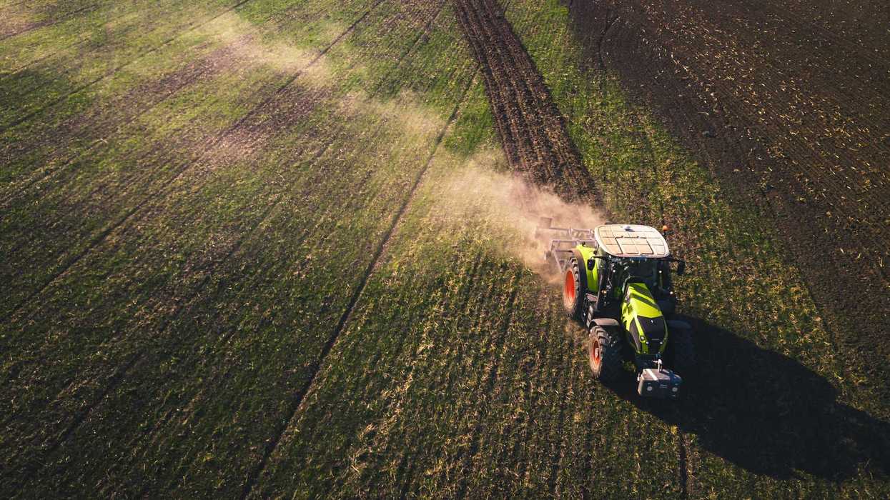 green and white tractor on green grass field during daytime.