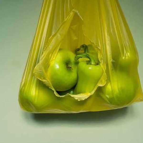Green apples and peppers in a yellow plastic bag