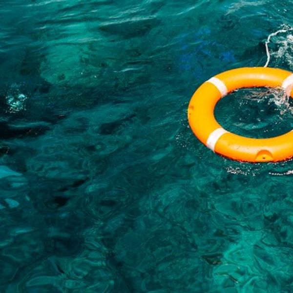 Green ocean water with an orange life preserver floating in the water