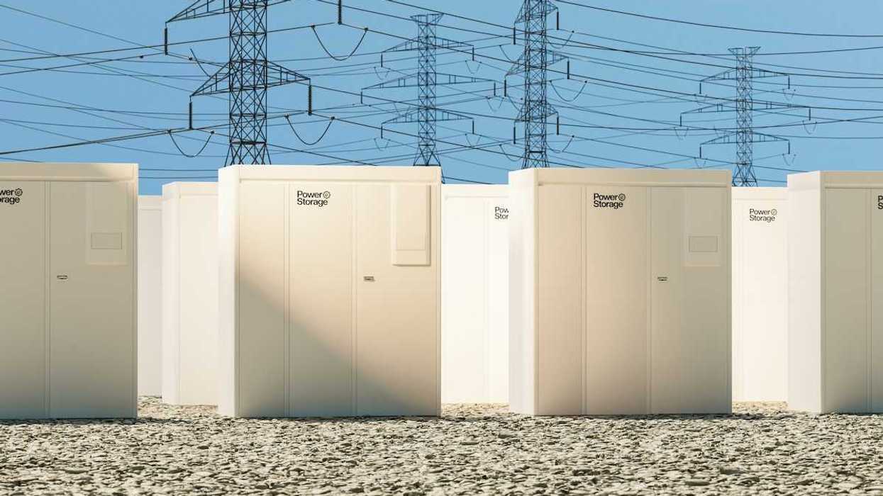 Grid-scale batteries aligned in rows with transmission lines behind