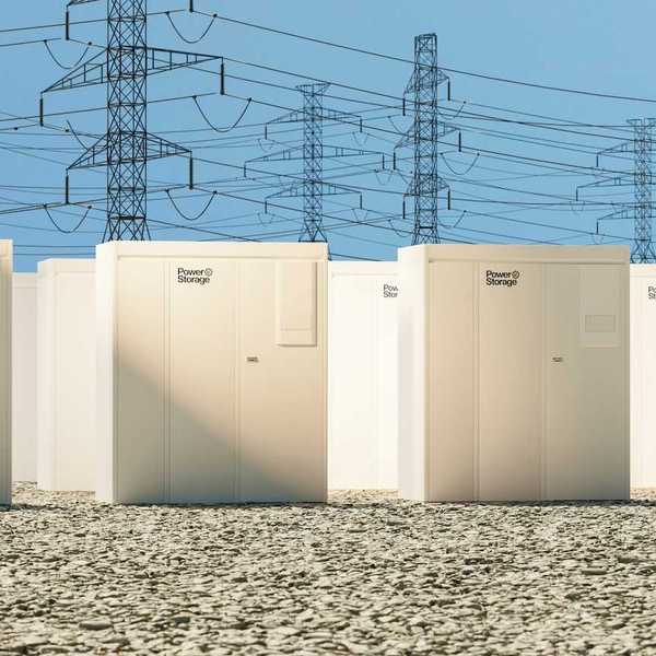 Grid-scale batteries aligned in rows with transmission lines behind