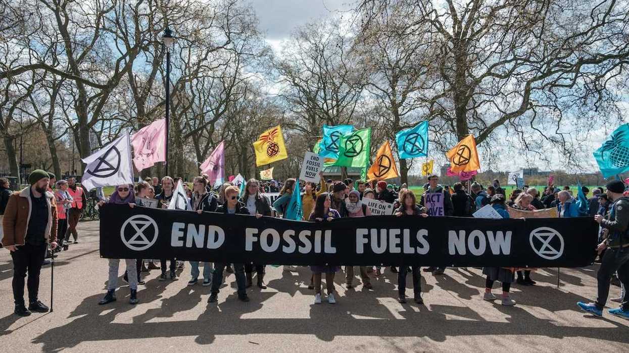 Group of activists marching , holding a banner that reads "END FOSSIL FUELS NOW."