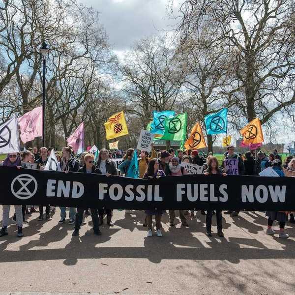 Group of activists marching , holding a banner that reads "END FOSSIL FUELS NOW."