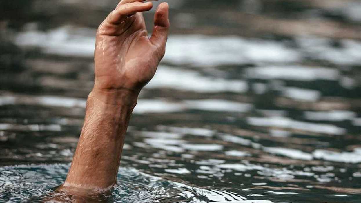 Hand and partially submerged forearm sticking out of floodwaters, one finger pointing up