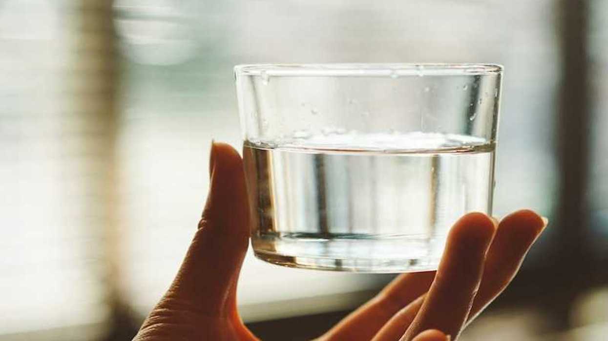 Hand holding a glass of water up to the light