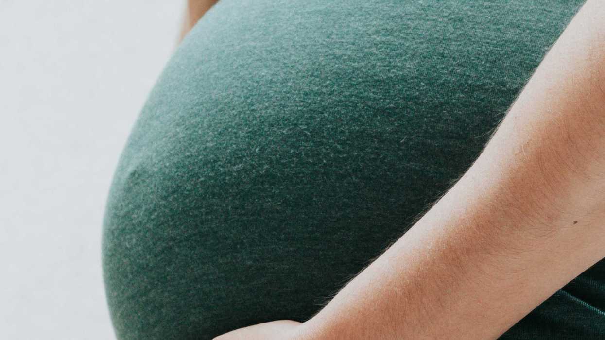 Hands holding pregnant belly.