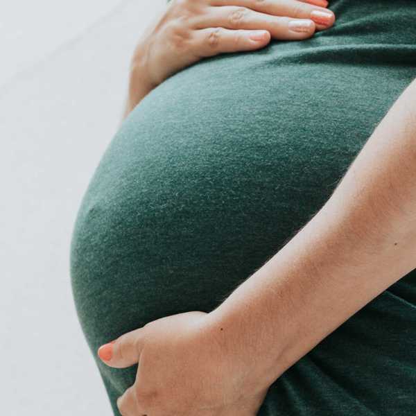 Hands holding pregnant belly.