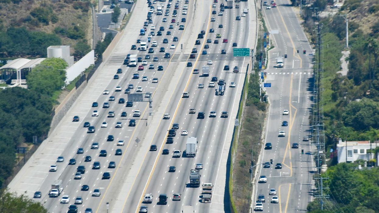 Heavy traffic on a multi-lane highway through hills.