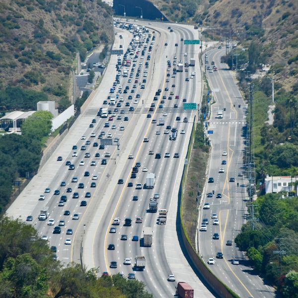 Heavy traffic on a multi-lane highway through hills.