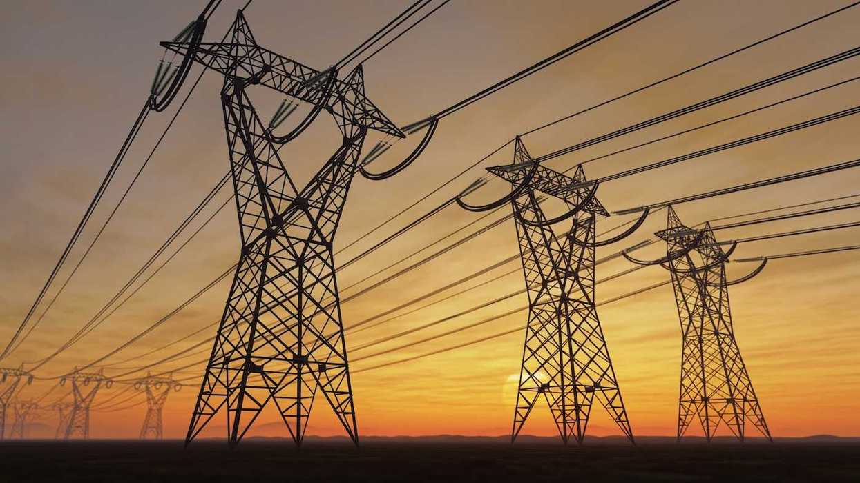 High voltage transmission towers against a setting or rising sun