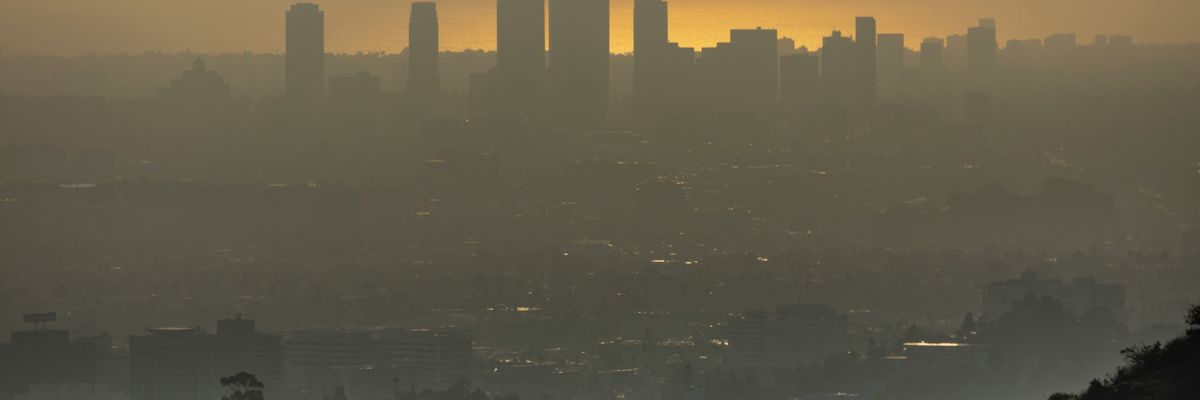 hikers in LA silhouetted against a hazy urban landscape at sunset.