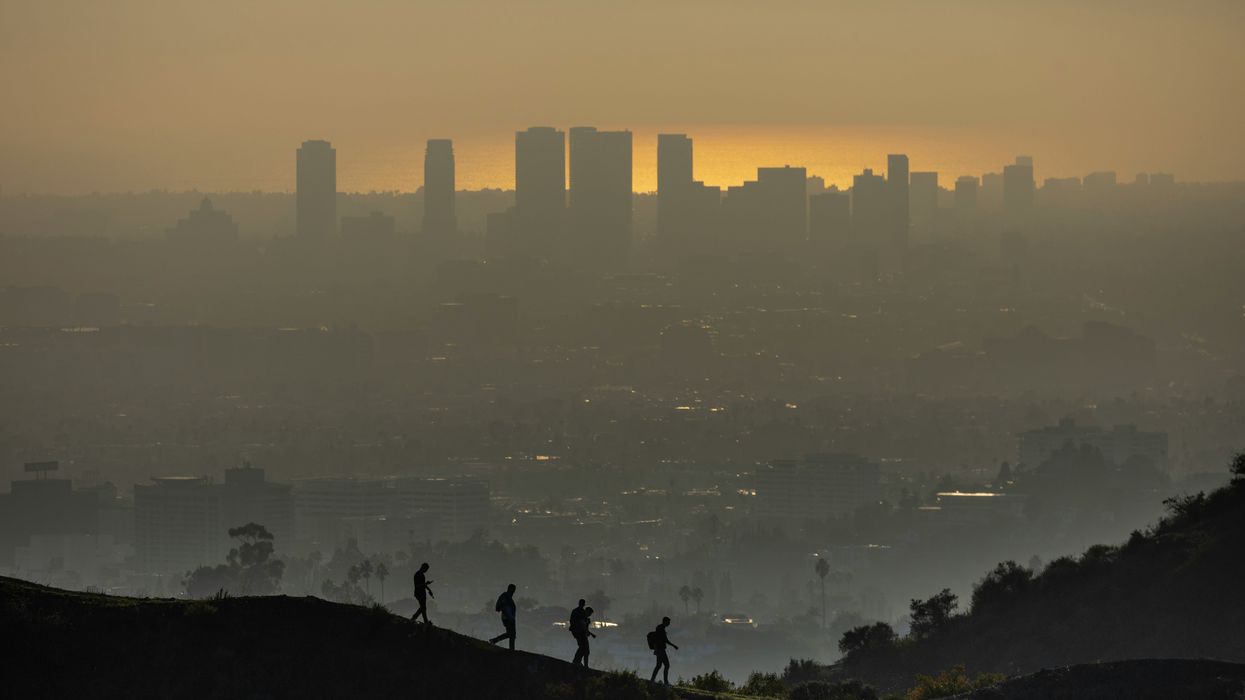 hikers in LA silhouetted against a hazy urban landscape at sunset.