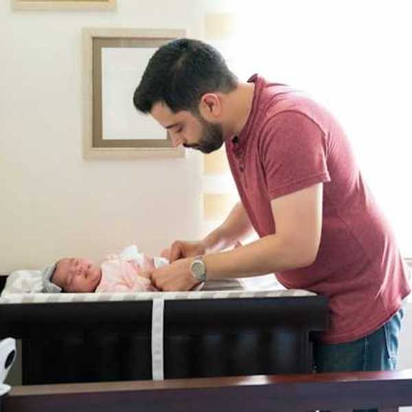 Hispanic father changing his newborn baby girl's diaper