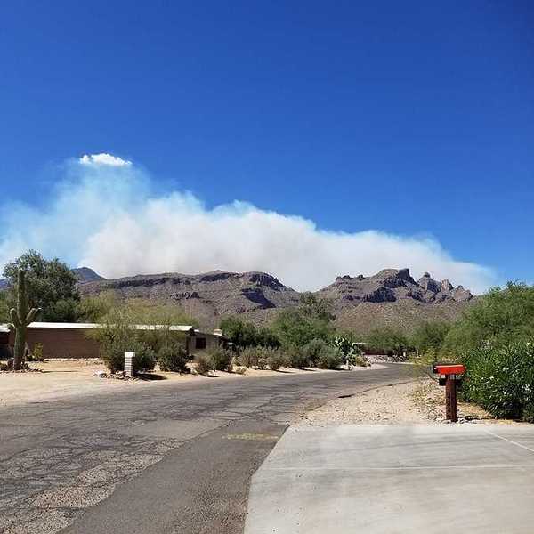 Homes in a dry landscape with wildfire smoke billowing in the background