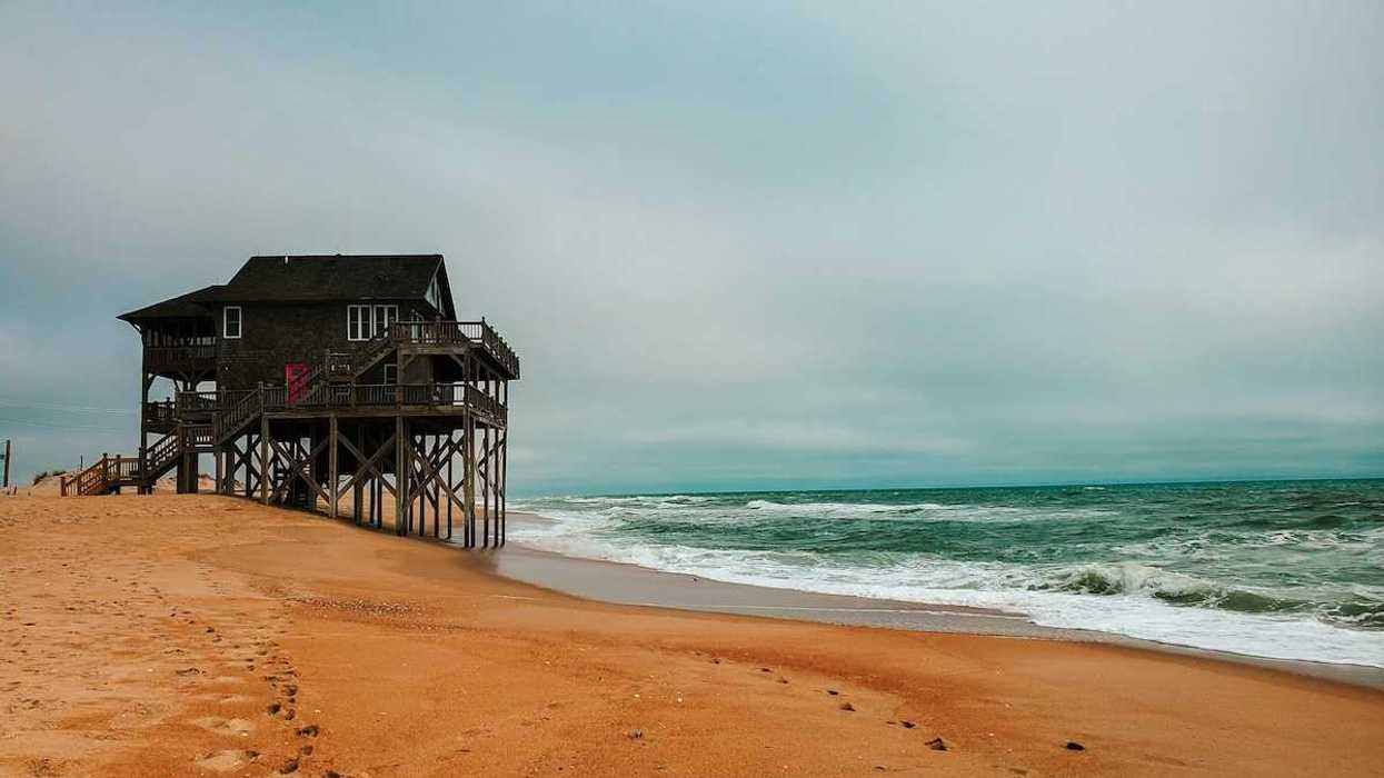 House on stilts precariously positioned next to ocean in Rodanthe, North Carolina
