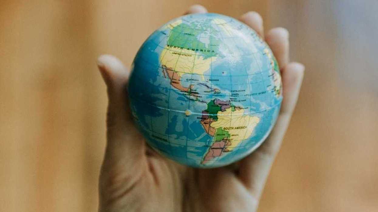 Human hand holding a miniature globe showing both North and South America