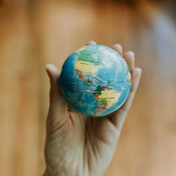 Human hand holding a miniature globe showing both North and South America