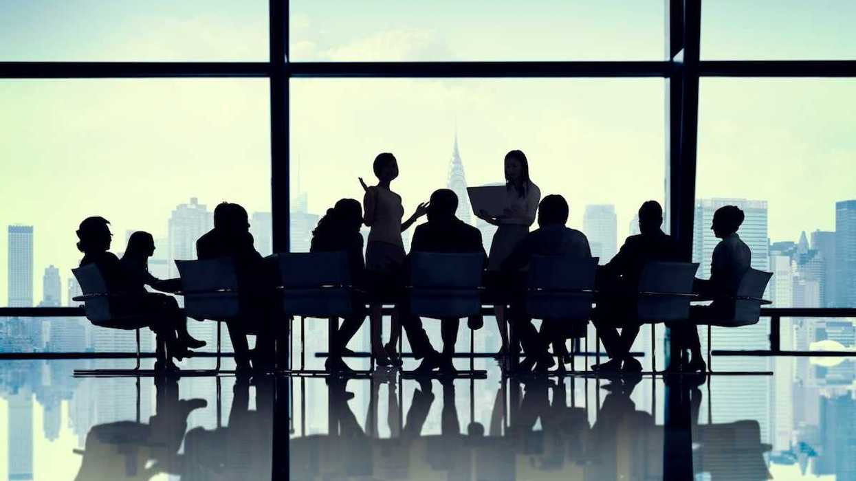 Illustration of silhouetted buisiness people gathered around a conference table against a cityscape background