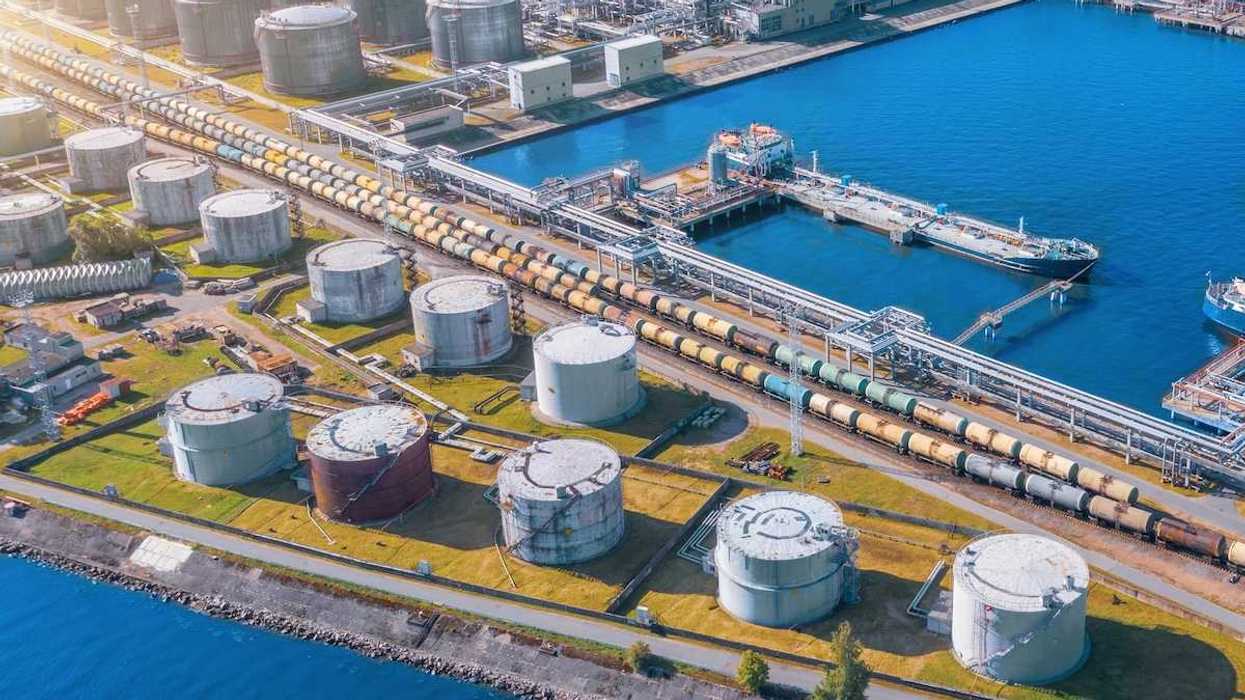 Import/export shipping terminal intersected by a rail line stacked with railroad tanker cars for liquid transport